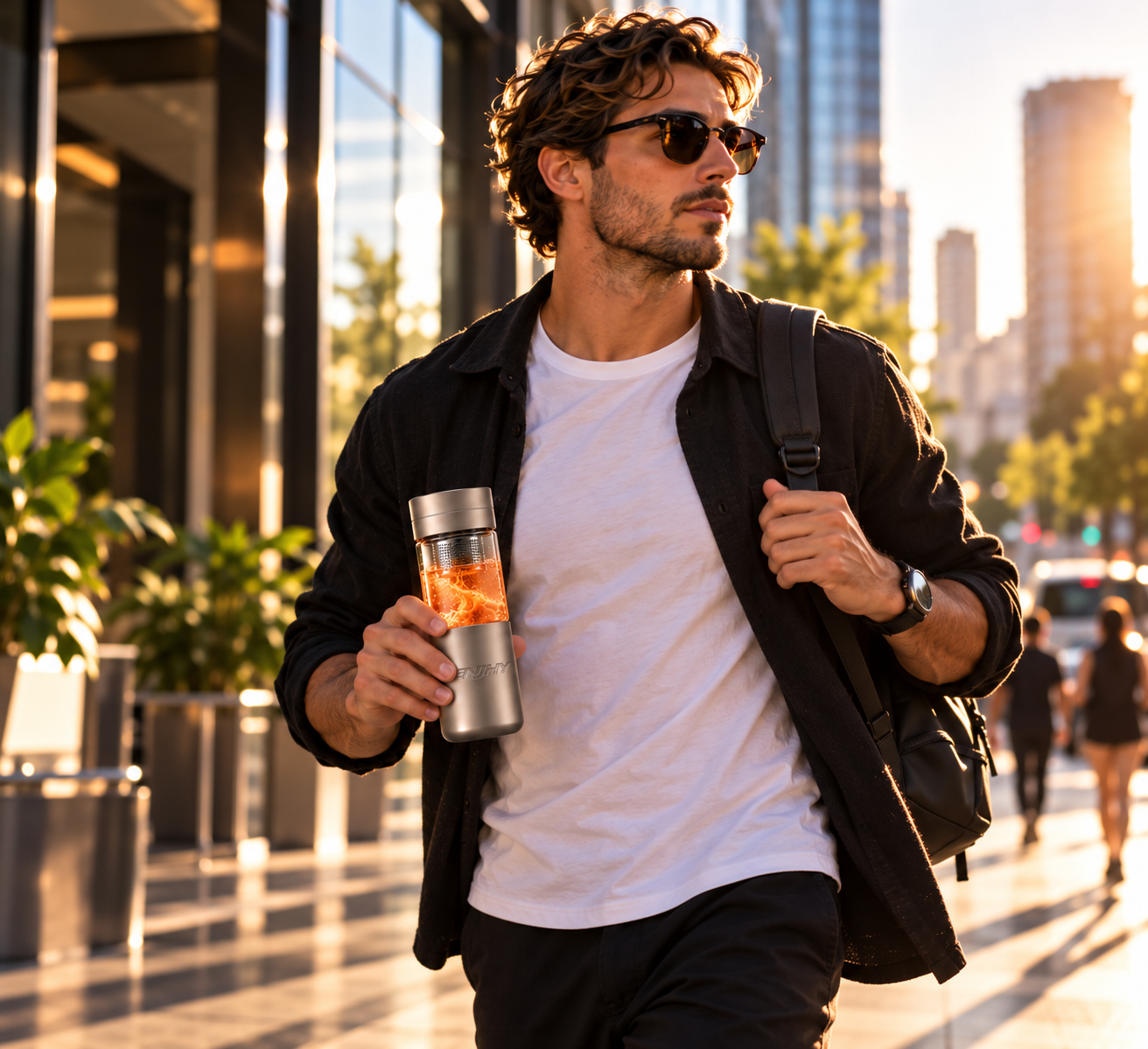 Man in sunglasses walking a city sidewalk at golden hour carrying an ENJHY Energy bottle with amber contents